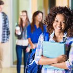 happy college student posing near her friends on campus